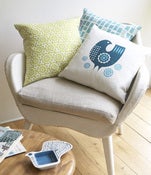 Image of teal bird cushion on white linen